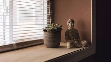 Una ventana con una planta en maceta y una estatua de Buda en el alféizar.
