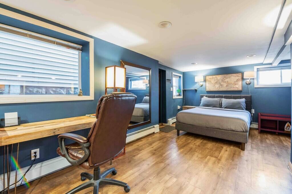 A bedroom with a bed, a desk, and a chair.