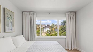 Un dormitorio con una cama grande, una ventana con cortinas y un cuadro en la pared.