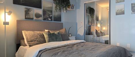 A bedroom with a bed, bedside tables, a mirror, and wall art.