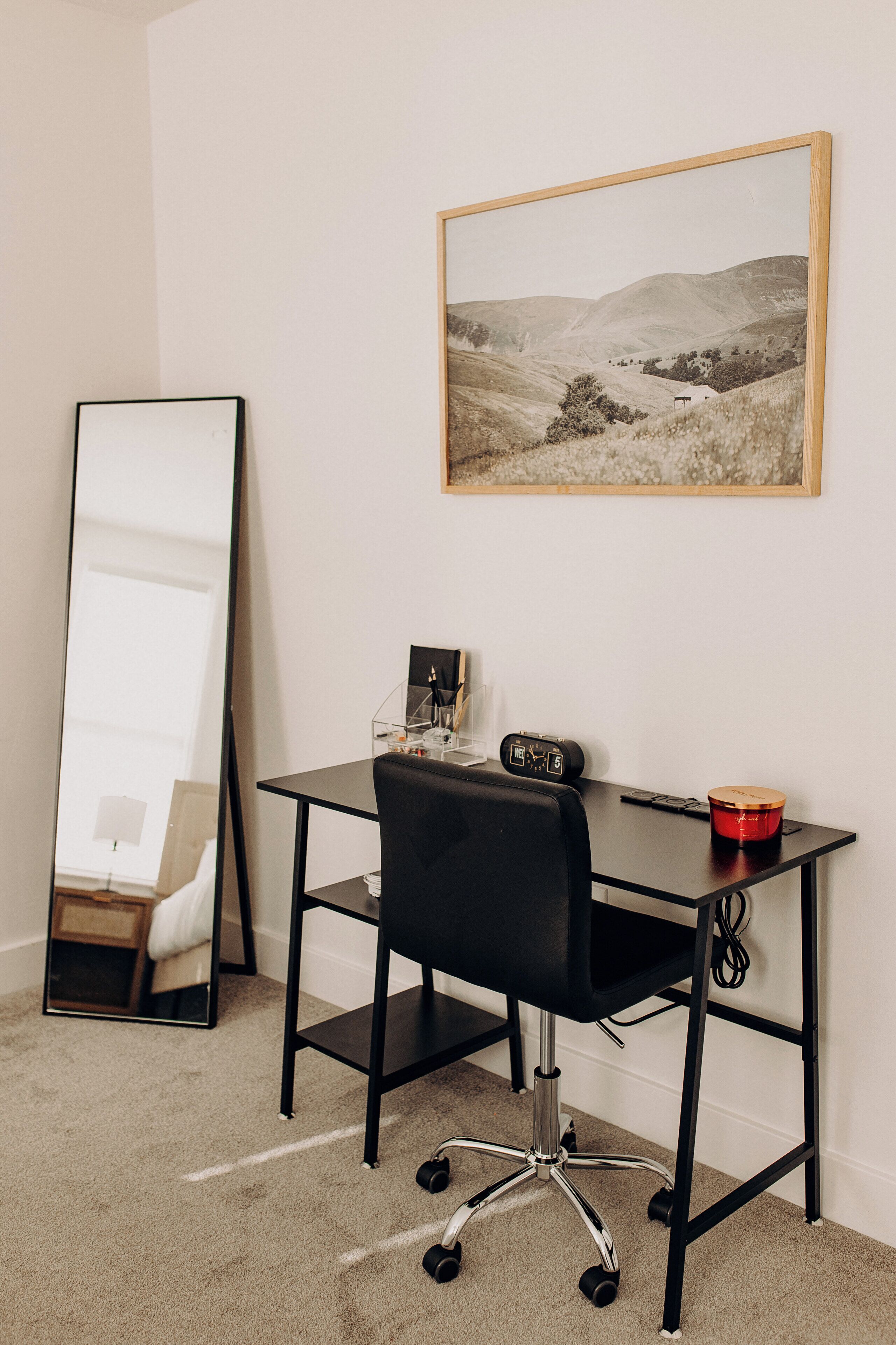 A room with a desk, chair, and a large mirror.