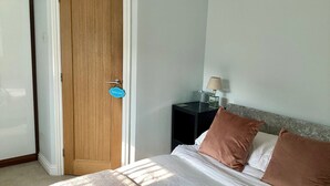 Ein Schlafzimmer mit einem Bett, einem Nachttisch mit Lampe und einer Tür mit der Aufschrift 'Bad'.