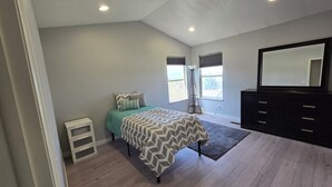 Quarto com cama, penteadeira, espelho e janela.