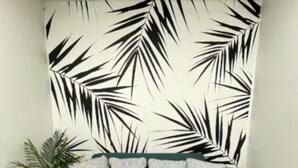 A teal sofa with three pillows against a wall with a black and white leaf pattern. - The Vice City Suite•Private Stay+Free Parking in the Heart of Miami (Miami)