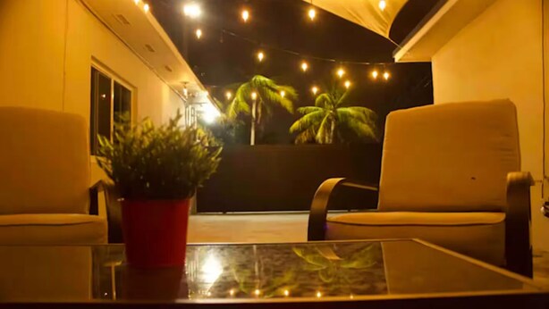 A room with two white chairs, a glass table, and a red potted plant. - The Vice City Suite•Private Stay+Free Parking in the Heart of Miami (Miami)