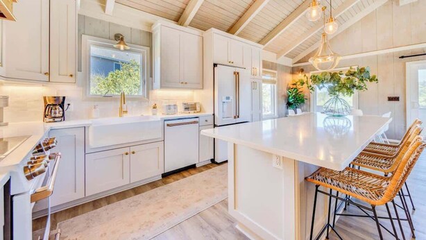 A modern kitchen with white cabinetry, a large island with bar stools, and pendant lighting.