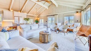 A spacious living room with a high ceiling, large windows, and a modern design.