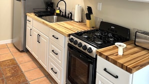 A kitchen with white cabinets, a stainless steel refrigerator, a microwave, a stove, and a toaster.