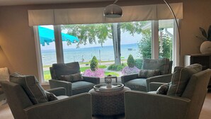 Un salon avec vue sur un lac, deux fauteuils, une table basse et une lampe.