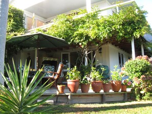 A covered porch with outdoor furniture, potted plants, and a lawn. - Peaceful 1-bedroom apartment in charming Russell perfect fora relaxing stay (Russell)