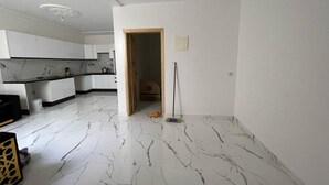 A modern kitchen with white cabinets and a marble floor. - Air-conditioned apartment for rent in SAÏDIA (Saïdia)