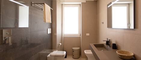 Un baño moderno con un espejo grande, un lavabo, un inodoro y una zona de ducha.