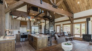 Una cocina amplia con una isla central, vigas de madera y una escalera en espiral.