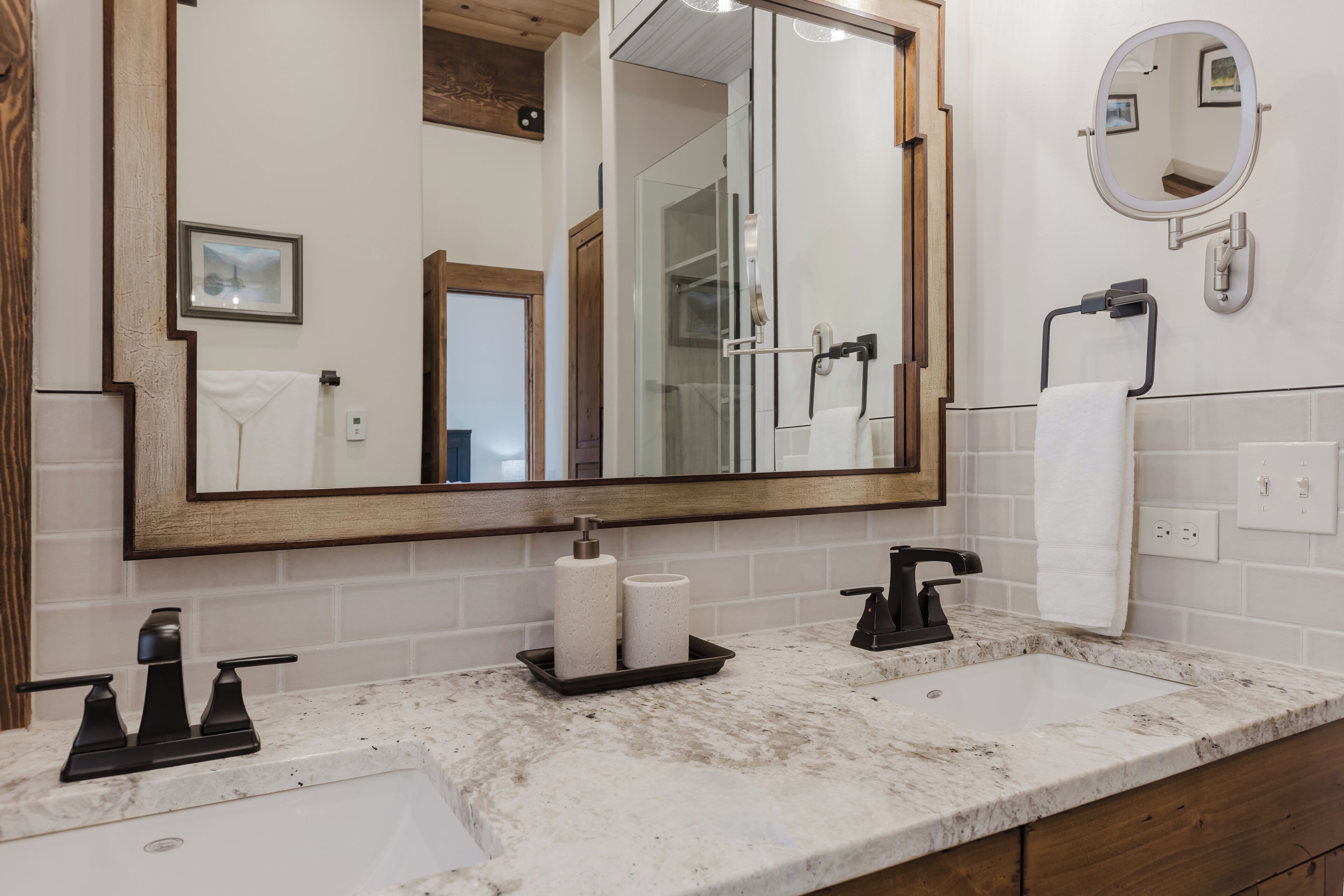 A bathroom with a large mirror, two sinks, and a shower.