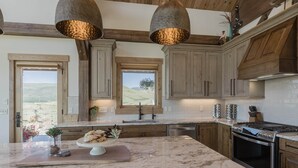 Una cocina con armarios de madera, encimera de mármol e iluminación colgante.