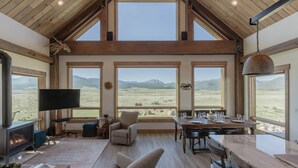 Un salón amplio con chimenea, ventanas grandes y una zona de comedor.