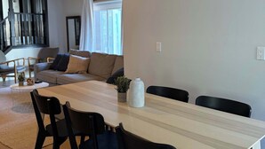 Ein moderner Essbereich mit einem Holztisch, schwarzen Stühlen und einer weißen Vase.