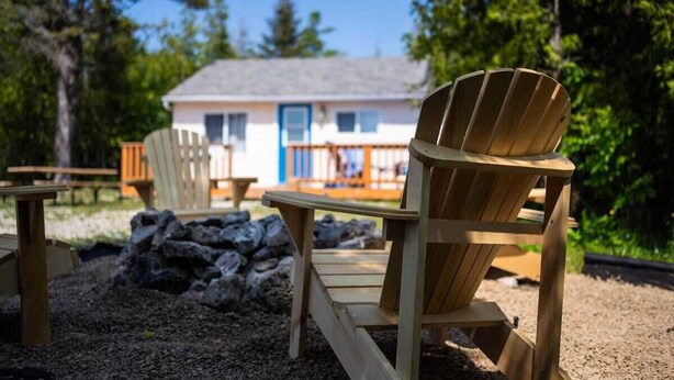 Una silla Adirondack de madera en un jardín, con una casa al fondo.