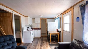 Un espacio habitable compacto con kitchenette, comedor y dos zonas de estar.
