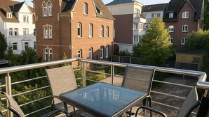 A balcony with a glass table and four chairs, overlooking a row of houses. - Central new-build apartment in Siegen (Siegen)