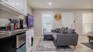 A modern kitchen with stainless steel appliances, a gray sofa, and a decorative wall piece. - The Travelers Studio Columbus (Columbus)