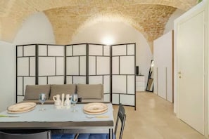 A dining area with a table set for two, a brick ceiling, and a white partition with a grid pattern.