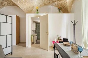 A modern interior with a dining area, a kitchen, and an open doorway leading to a bathroom.