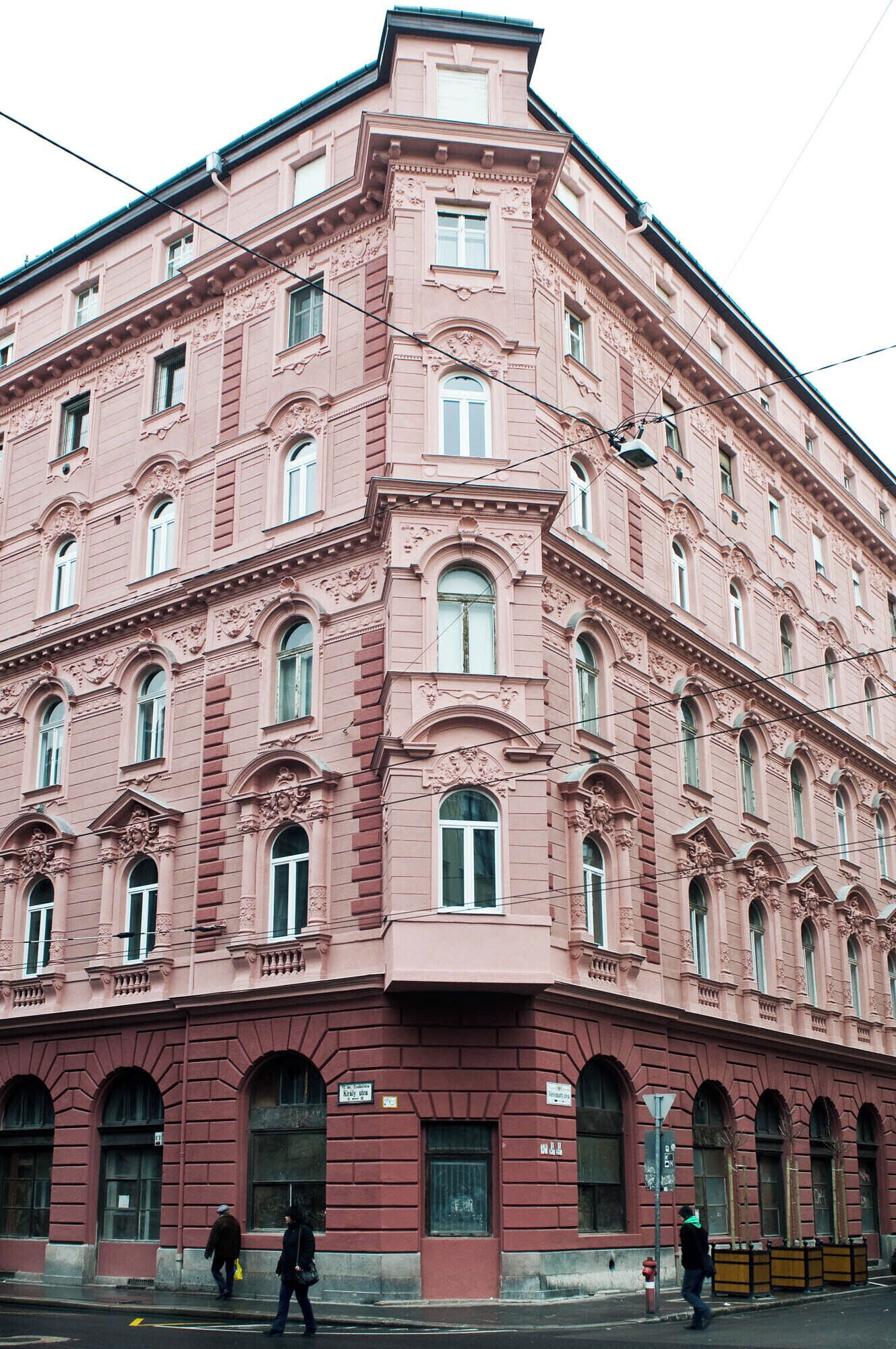 A pink building with multiple windows and a corner entrance.