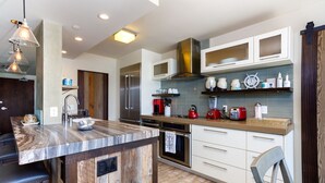 A modern kitchen with a marble island, stainless steel appliances, and wooden accents.