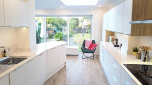 Une cuisine moderne avec des meubles blancs, un plan de travail noir et une lucarne.
