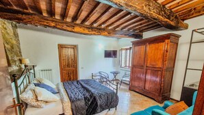 A bedroom with a bed, a wooden wardrobe, a small table with chairs, and a blue sofa.