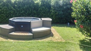 A circular outdoor hot tub with a built-in seating area, surrounded by a grassy lawn and hedges. - Villa Magnolia - Pula (Pula)