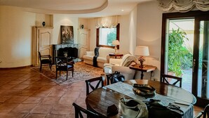 A spacious living room with a fireplace, a dining area with a table and chairs, and a view of the outdoors through a glass door. - Villa Magnolia - Pula (Pula)