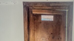 A wooden door with a metal handle and a small sign above it. - Romano Apartment - Trapani (Trapani)