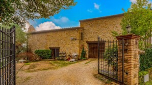 A stone building with a gravel driveway and a metal gate. - Monte Oliveto House - Apartment 3 (Bettona)