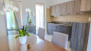 Una cocina moderna con armarios de madera, un refrigerador de acero inoxidable y una zona de comedor con una mesa y sillas de madera.