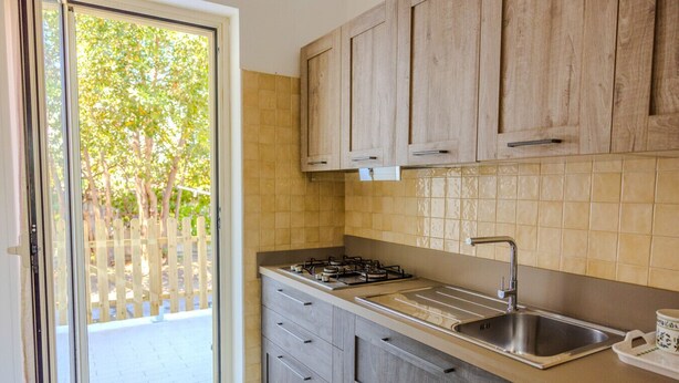 Una cocina con armarios de madera, una estufa a gas y un lavamanos.