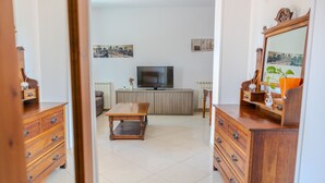 Una sala de estar con televisor, muebles de madera y obras de arte con vistas a la ciudad.