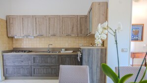 Una cocina con armarios de madera, una estufa a gas, un fregadero y un comedor con mesa y sillas.