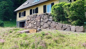 Une maison à deux étages avec un mur en pierre et une enseigne indiquant « Gîte Carlivia ».