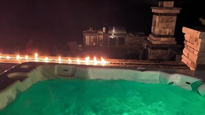 A hot tub with a green light, surrounded by a stone structure and a row of candles. - Spacious 5-bedroom house in nice Winfield with WiFi, Pool and Hot tub (Winfield)