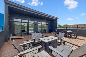 A rooftop patio with outdoor seating and a glass door entrance.
