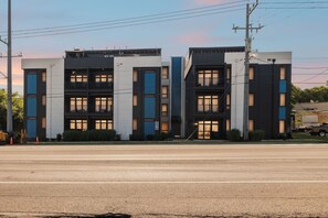 A modern multi-story building with a flat facade, large windows, and a mix of white and dark-colored panels.