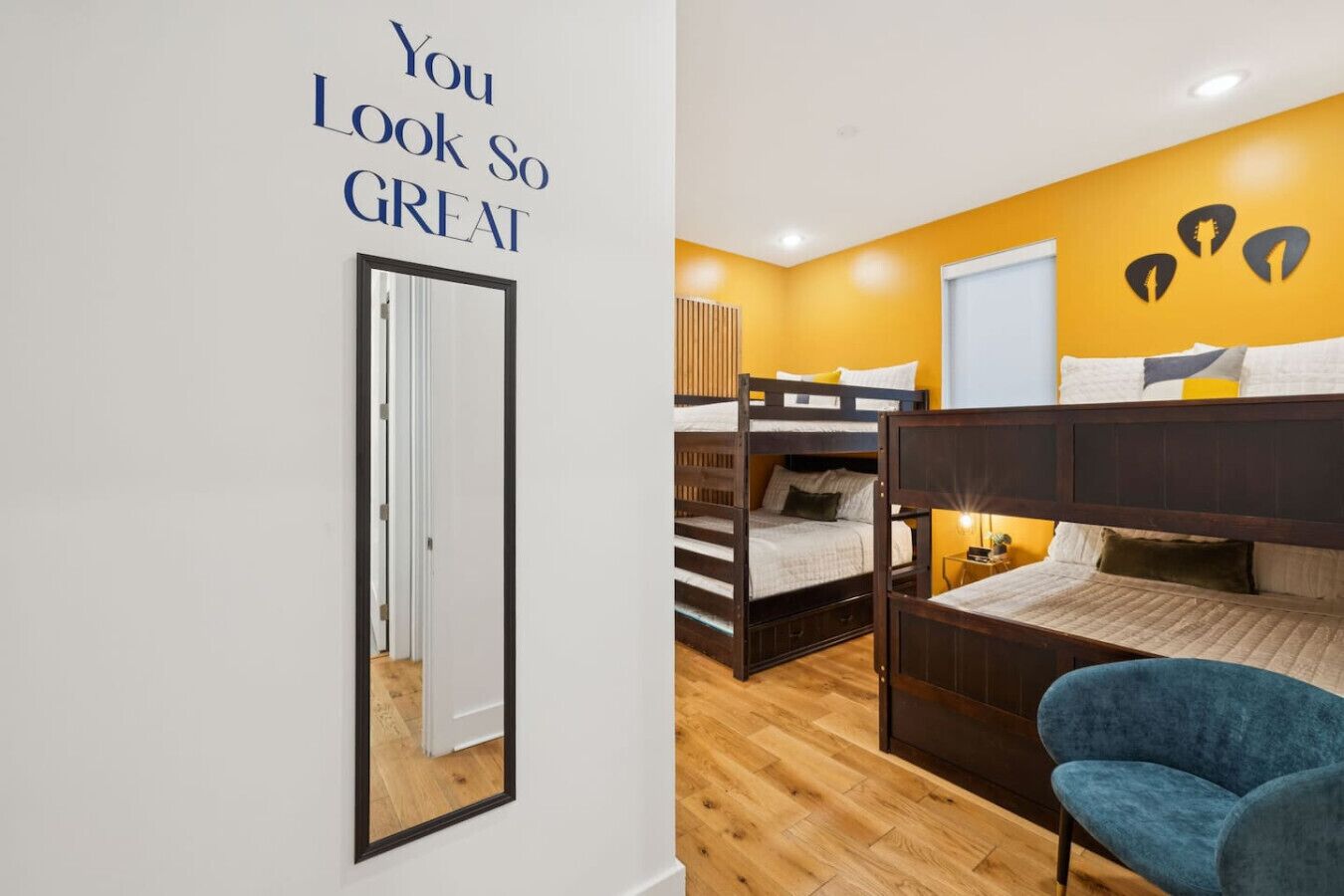 Un dormitorio con literas, un espejo y una frase motivacional en la pared.
