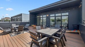 An outdoor patio area with wooden flooring, metal tables, and chairs.