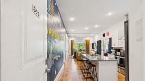 A modern kitchen with a central island, bar stools, and a view of the outdoors.