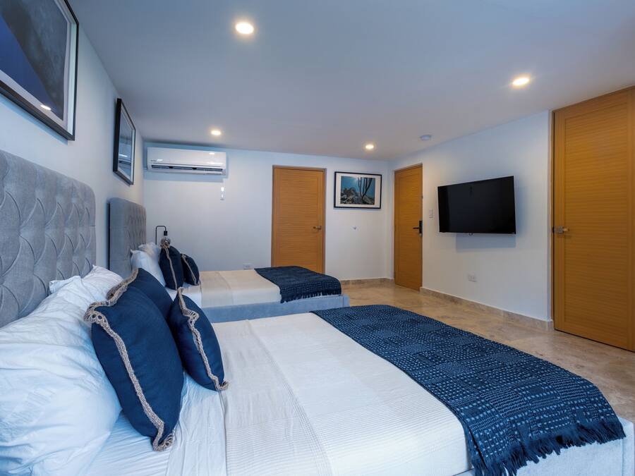 A hotel room with two beds, a flat-screen TV, and a large window.