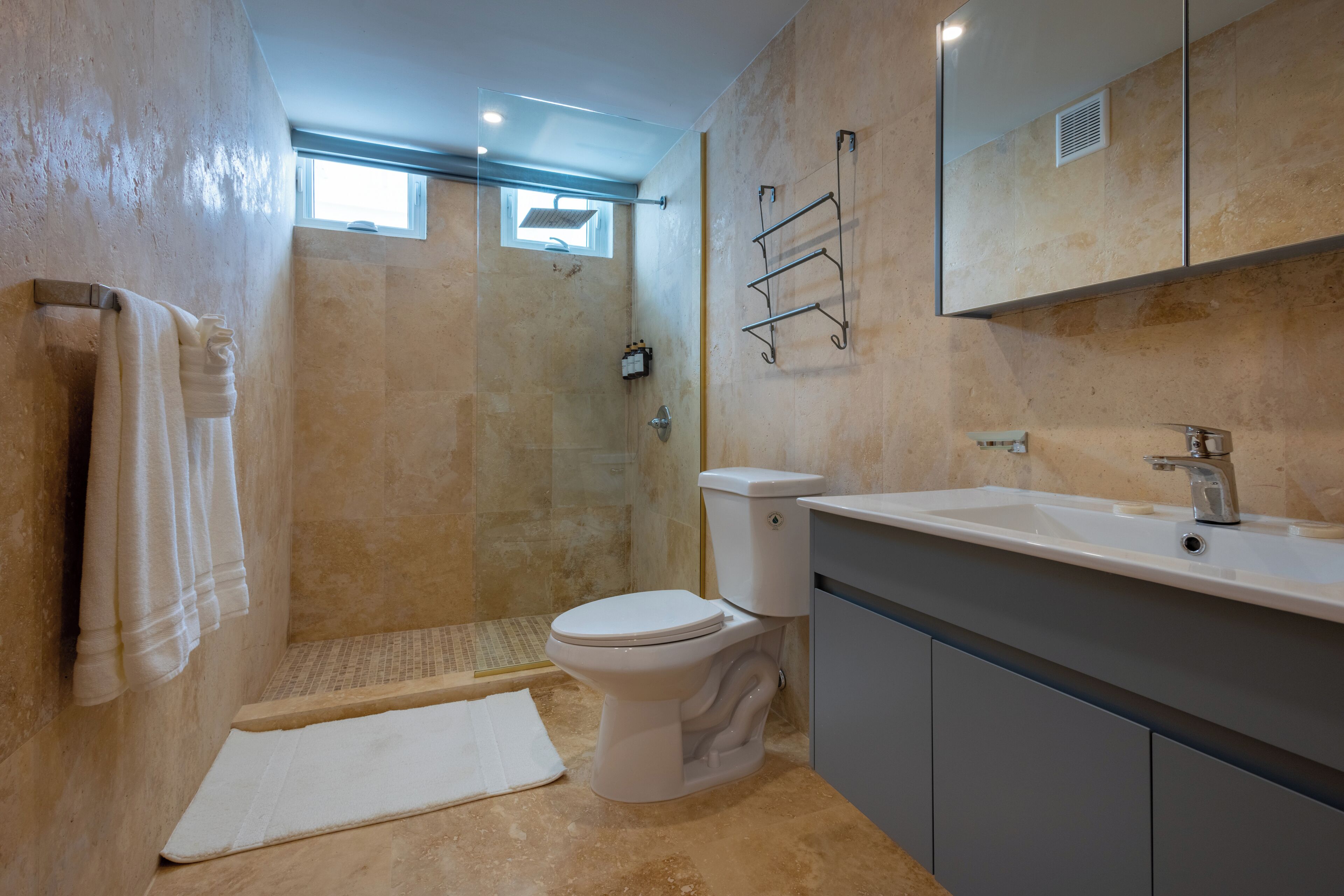 A bathroom with a shower, toilet, sink, and towel rack.