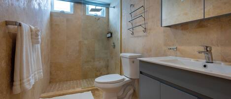 A bathroom with a shower, toilet, sink, and towel rack.