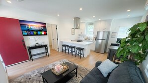 Ein modernes Wohnzimmer mit einem grauen Sofa, einem schwarzen Couchtisch mit einem dekorativen Korb und einer roten Akzentwand.